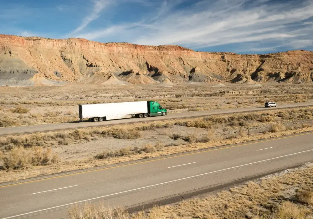 a white and sea green enclosed truck on a road between the mountains going from California to Alaska